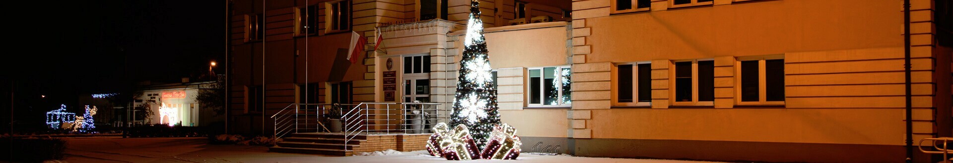 Baner top Gminy Dobrcz. Widok na Urząd Gminy w Dobrczu w zimowej odsłonie. Obok Urzędu stoi iluminacja świetlna w kształcie choinki.